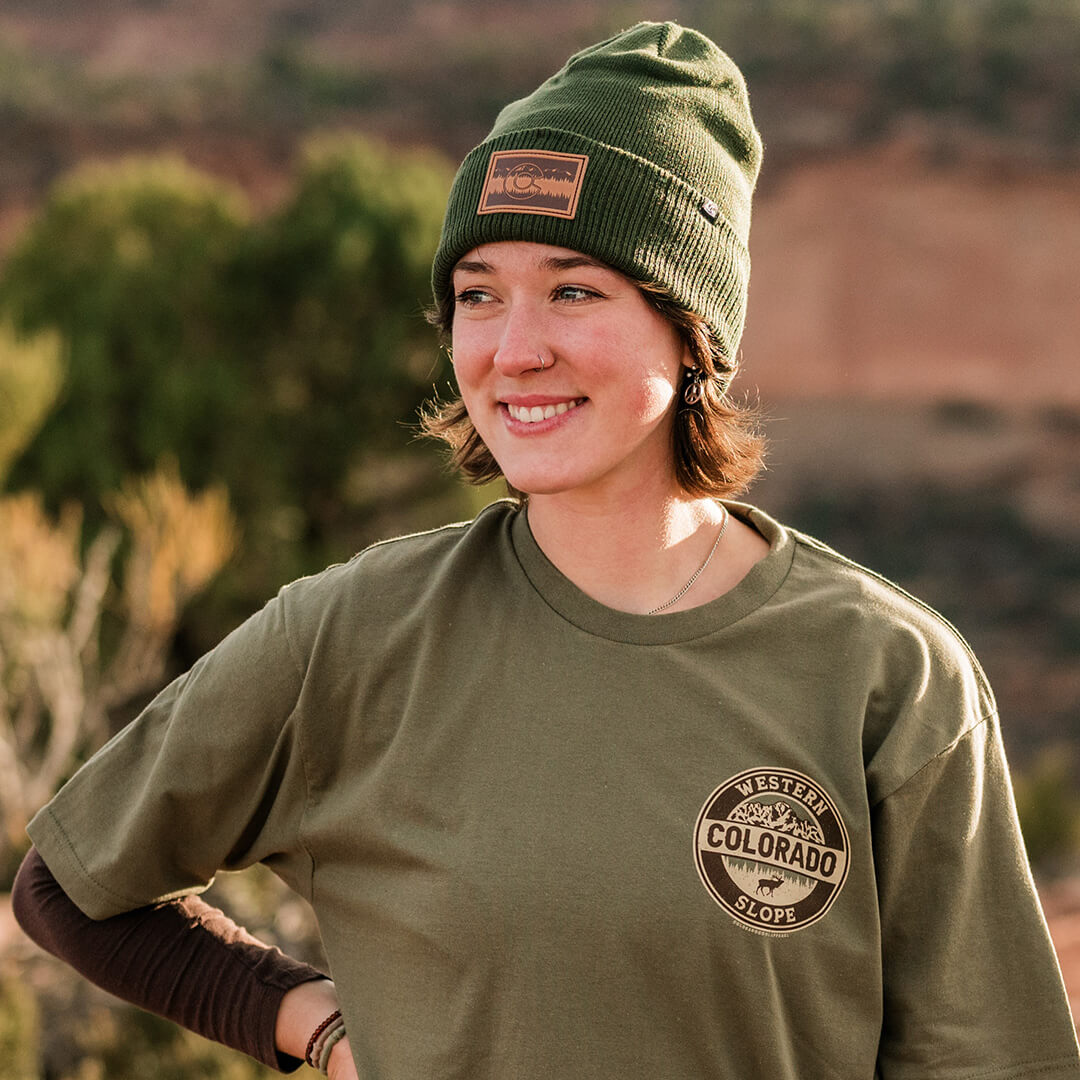 Photograph of the Treeline Beanie being worn on a woman who's smiling and wearing a similar colored green shirt.